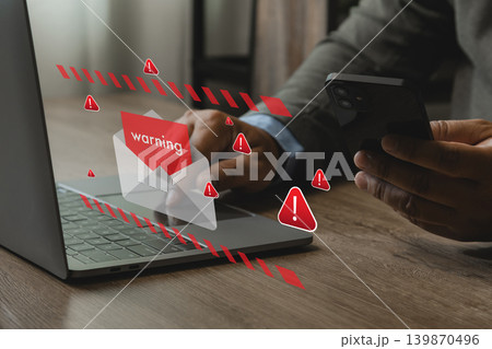 Person holding smartphone near laptop with phishing email warning icons and spam alert interface, representing cyber security risk, fake text message scam, online fraud, and data protection. 139870496