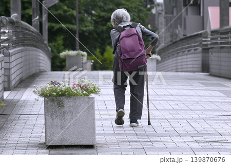 日本の横浜都市景観 腰が曲がった杖の高齢女性。リュックを背負い…。歩道橋の階段が困難で遠回り 日本の横浜都市景観 腰が曲がった杖の高齢女性。リュックを背負い…。歩道橋の階段が困難で遠回り 139870676