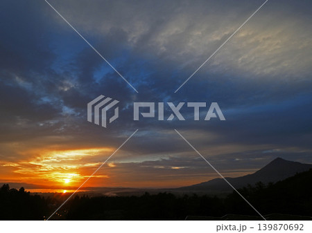猪苗代湖対岸に沈む夕日。オレンジ色に輝く太陽と湖面からの青空へのグラデーションと磐梯山が綺麗だ。 猪苗代湖対岸に沈む夕日。オレンジ色に輝く太陽と湖面からの青空へのグラデーションと磐梯山が綺麗だ。 139870692