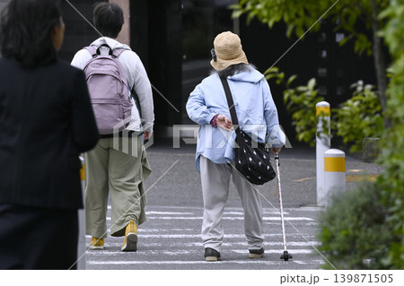 日本の横浜都市景観 腰を曲げた杖の高齢女性。横断中…左隣に優しそうな女性が同伴=横浜市内で 日本の横浜都市景観 腰を曲げた杖の高齢女性。横断中…左隣に優しそうな女性が同伴=横浜市内で 139871505
