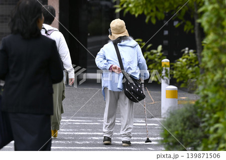 日本の横浜都市景観 腰を曲げた杖の高齢女性。横断中…左隣に優しそうな女性が同伴=横浜市内で 日本の横浜都市景観 腰を曲げた杖の高齢女性。横断中…左隣に優しそうな女性が同伴=横浜市内で 139871506