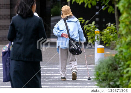 日本の横浜都市景観 腰を曲げた杖の高齢女性。横断中…左隣に優しそうな女性が同伴=横浜市内で 日本の横浜都市景観 腰を曲げた杖の高齢女性。横断中…左隣に優しそうな女性が同伴=横浜市内で 139871508