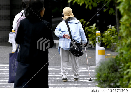日本の横浜都市景観 腰を曲げた杖の高齢女性。横断中…左隣に優しそうな女性が同伴=横浜市内で 日本の横浜都市景観 腰を曲げた杖の高齢女性。横断中…左隣に優しそうな女性が同伴=横浜市内で 139871509