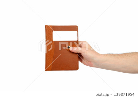 male hand holding a closed brown notebook isolated on a white background male hand holding a closed brown notebook isolated on a white background 139871954