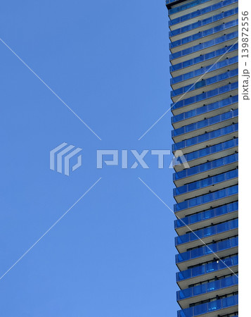 Skyscraper against clear blue sky creating urban minimalistic background with copy space Skyscraper against clear blue sky creating urban minimalistic background with copy space 139872556