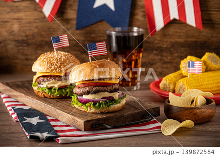 Cheeseburgers with American flags and barbecue party decorations for Fourth of July Cheeseburgers with American flags and barbecue party decorations for Fourth of July 139872584