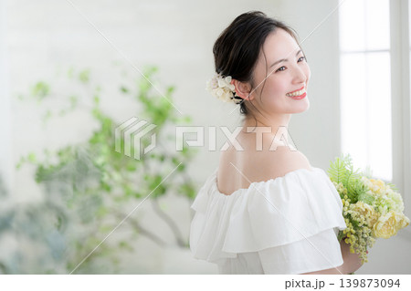 自然光の窓辺で花束を持って笑顔の日本人女性、花嫁やブライダルイメージ 振り返る横顔 自然光の窓辺で花束を持って笑顔の日本人女性、花嫁やブライダルイメージ 振り返る横顔 139873094