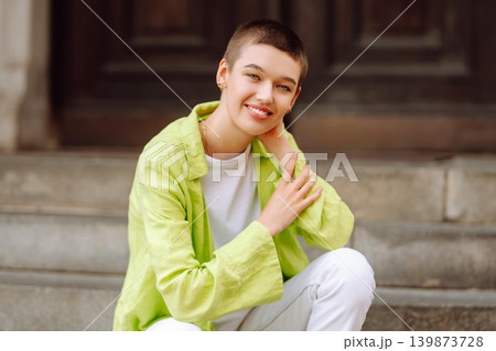 Stylish young woman with short haircut posing on city streets. The concept of fashion, style. 139873728
