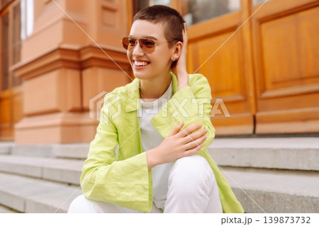 Stylish young woman with short haircut posing on city streets. The concept of fashion, style. 139873732