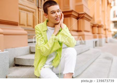 Stylish young woman with short haircut posing on city streets. The concept of fashion, style. 139873739