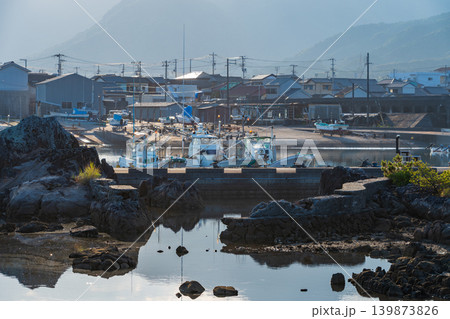 朝の静けさに包まれた漁港と水面に映る船の影 朝の静けさに包まれた漁港と水面に映る船の影 139873826
