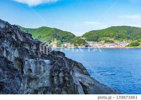 手前の荒々しい奇岩の向こうに見える穏やかな海の集落 手前の荒々しい奇岩の向こうに見える穏やかな海の集落 139873861