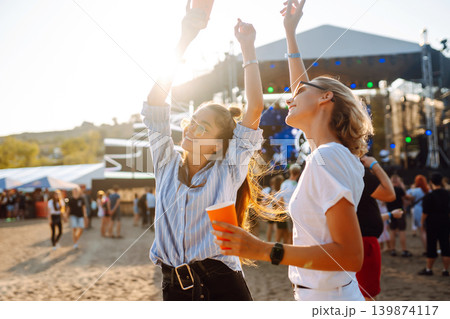 Two woman having great time at music festival. Girlfriends rinking beer at Beach party. Lifestyle. 139874117