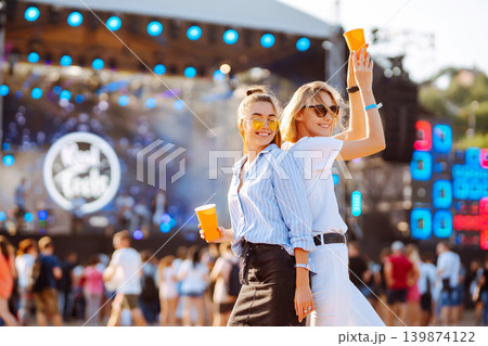 Two woman having great time at music festival. Girlfriends rinking beer at Beach party. Lifestyle. Two woman having great time at music festival. Girlfriends rinking beer at Beach party. Lifestyle. 139874122
