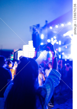 Holding a mobile phone in hands and shooting photo or video content. Youth, party, vacation concept. 139874136