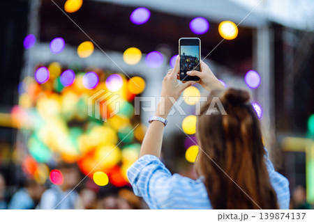 Holding a mobile phone in hands and shooting photo or video content. Youth, party, vacation concept. 139874137