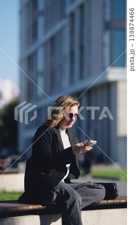 Caucasian woman with curly hair using her mobile phone outdoors. Close-up. Communication technology and modern lifestyle concept Caucasian woman with curly hair using her mobile phone outdoors. Close-up. Communication technology and modern lifestyle concept 139874466