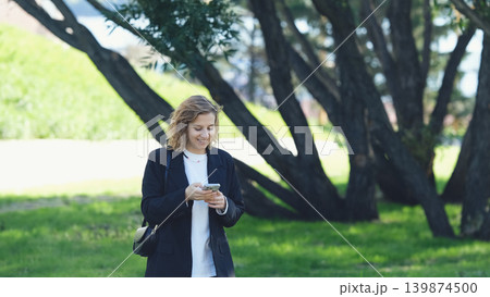 Caucasian woman with curly hair using her mobile phone outdoors. Close-up. Communication technology and modern lifestyle concept Caucasian woman with curly hair using her mobile phone outdoors. Close-up. Communication technology and modern lifestyle concept 139874500
