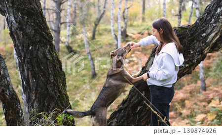Young woman walking with a dog in an autumn forest Young woman walking with a dog in an autumn forest 139874926