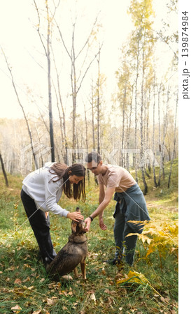 A woman and a man in love are walking in an autumn forest, in tall yellow grass, in fern leaves, a dog is walking next to them. A married couple is relaxing in nature during a walk with their beloved A woman and a man in love are walking in an autumn forest, in tall yellow grass, in fern leaves, a dog is walking next to them. A married couple is relaxing in nature during a walk with their beloved 139874984