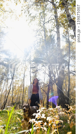 Young woman walking with a dog in an autumn forest 139875007