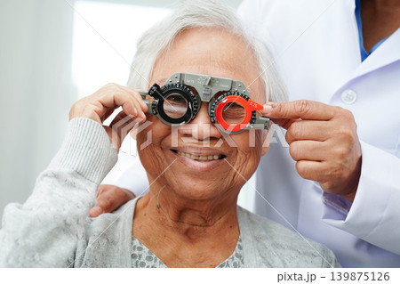 Optometrist checking Asian elderly woman ophthalmic vision eye test and using optical trial frame. Optometrist checking Asian elderly woman ophthalmic vision eye test and using optical trial frame. 139875126