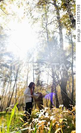 Young woman walking with a dog in an autumn forest Young woman walking with a dog in an autumn forest 139875398