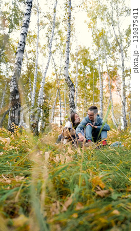 A woman and a man in love are walking in an autumn forest, in tall yellow grass, in fern leaves, a dog is walking next to them. A married couple is relaxing in nature during a walk with their beloved A woman and a man in love are walking in an autumn forest, in tall yellow grass, in fern leaves, a dog is walking next to them. A married couple is relaxing in nature during a walk with their beloved 139875411
