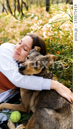Young woman walking with a dog in an autumn forest Young woman walking with a dog in an autumn forest 139875419