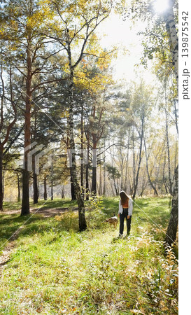 Young woman walking with a dog in an autumn forest Young woman walking with a dog in an autumn forest 139875542