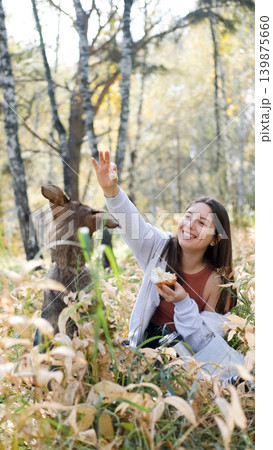 Young woman walking with a dog in an autumn forest Young woman walking with a dog in an autumn forest 139875660