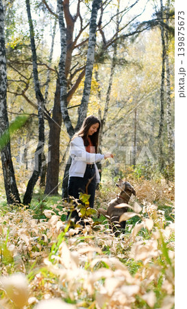 Young woman walking with a dog in an autumn forest Young woman walking with a dog in an autumn forest 139875673