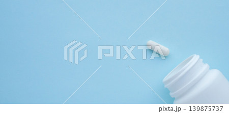 medicine pills capsule spilling out of bottle on blue background medicine pills capsule spilling out of bottle on blue background 139875737