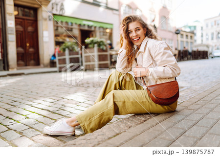 Fashionable young woman in good mood posing outdoors. Concept of enjoying weekend. Lifestyle concept Fashionable young woman in good mood posing outdoors. Concept of enjoying weekend. Lifestyle concept 139875787