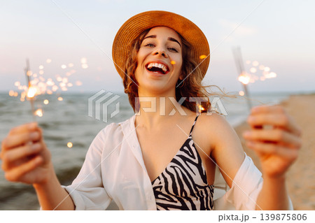 The sparklers in the hands of young woman on the beach. Summer holidays and lifestyle concept. The sparklers in the hands of young woman on the beach. Summer holidays and lifestyle concept. 139875806