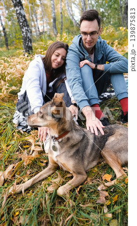 A woman and a man in love are walking in an autumn forest, in tall yellow grass, in fern leaves, a dog is walking next to them. A married couple is relaxing in nature during a walk with their beloved A woman and a man in love are walking in an autumn forest, in tall yellow grass, in fern leaves, a dog is walking next to them. A married couple is relaxing in nature during a walk with their beloved 139875813