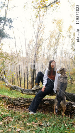 Young woman walking with a dog in an autumn forest Young woman walking with a dog in an autumn forest 139875822