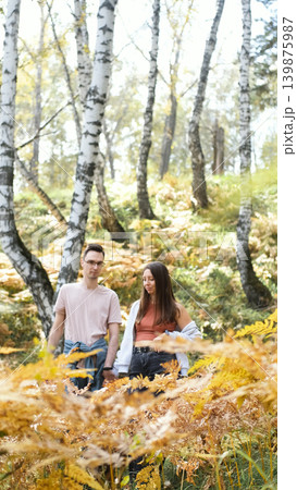 A young man and a girl in love are walking in an autumn park on a sunny autumn day. 139875987