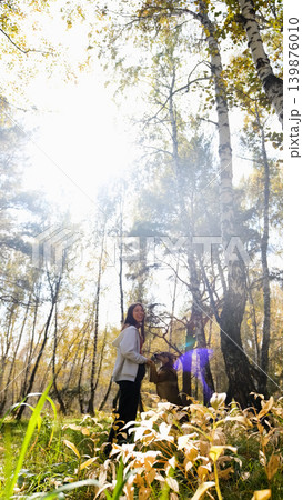 Young woman walking with a dog in an autumn forest Young woman walking with a dog in an autumn forest 139876010
