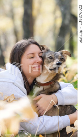 Young woman walking with a dog in an autumn forest Young woman walking with a dog in an autumn forest 139876022