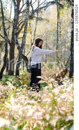 Young woman walking with a dog in an autumn forest 139876024