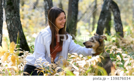 Young woman walking with a dog in an autumn forest 139876034