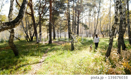 Young woman walking with a dog in an autumn forest 139876038