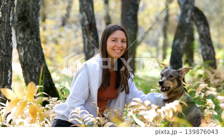 Young woman walking with a dog in an autumn forest Young woman walking with a dog in an autumn forest 139876043