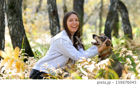 Young woman walking with a dog in an autumn forest Young woman walking with a dog in an autumn forest 139876045
