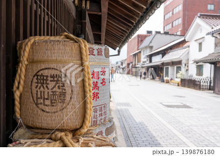 日本の酒蔵入口に置かれた菰樽と歴史的な街並み 139876180
