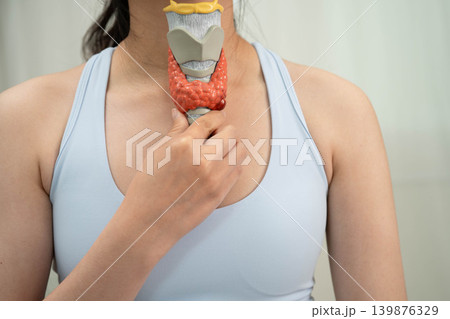 Hyperthyroidism, Overactive Thyroid, Thyroid Lymphoma, Asian woman with thyroid gland human anatomy model. Hyperthyroidism, Overactive Thyroid, Thyroid Lymphoma, Asian woman with thyroid gland human anatomy model. 139876329