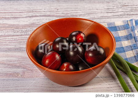 Black cherry tomatoes in terracotta bowl with green onions on rustic wood table Black cherry tomatoes in terracotta bowl with green onions on rustic wood table 139877066