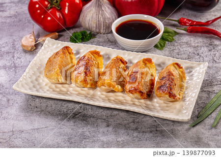 Golden fried gyoza dumplings on plate with dipping sauce and vegetables Golden fried gyoza dumplings on plate with dipping sauce and vegetables 139877093