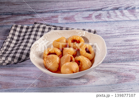 Pitted longan fruit in white ceramic bowl on colorful rustic wood table with napkin Pitted longan fruit in white ceramic bowl on colorful rustic wood table with napkin 139877107